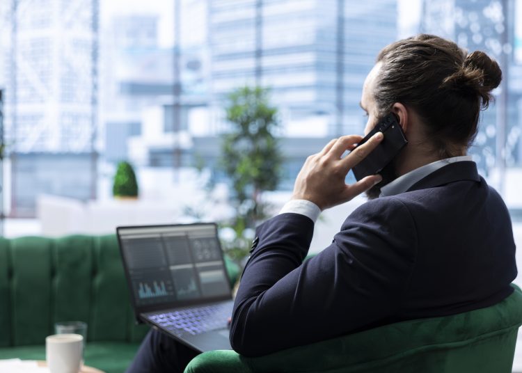 CEO discusses a potential partnership over the phone with investors, briefing them about the company sales numbers. Boss aligning strategic business ideas to ensure enterprise growth.