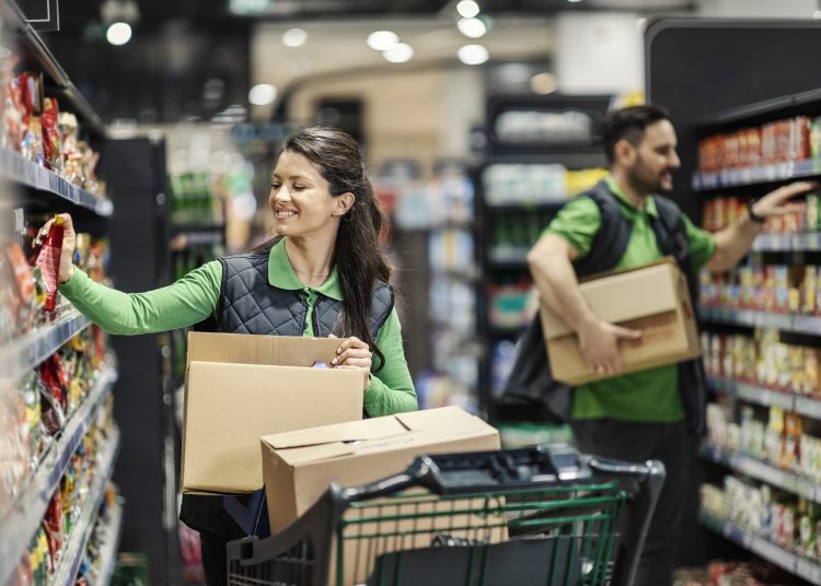 Happy employees putting products on shelves in supermarket.