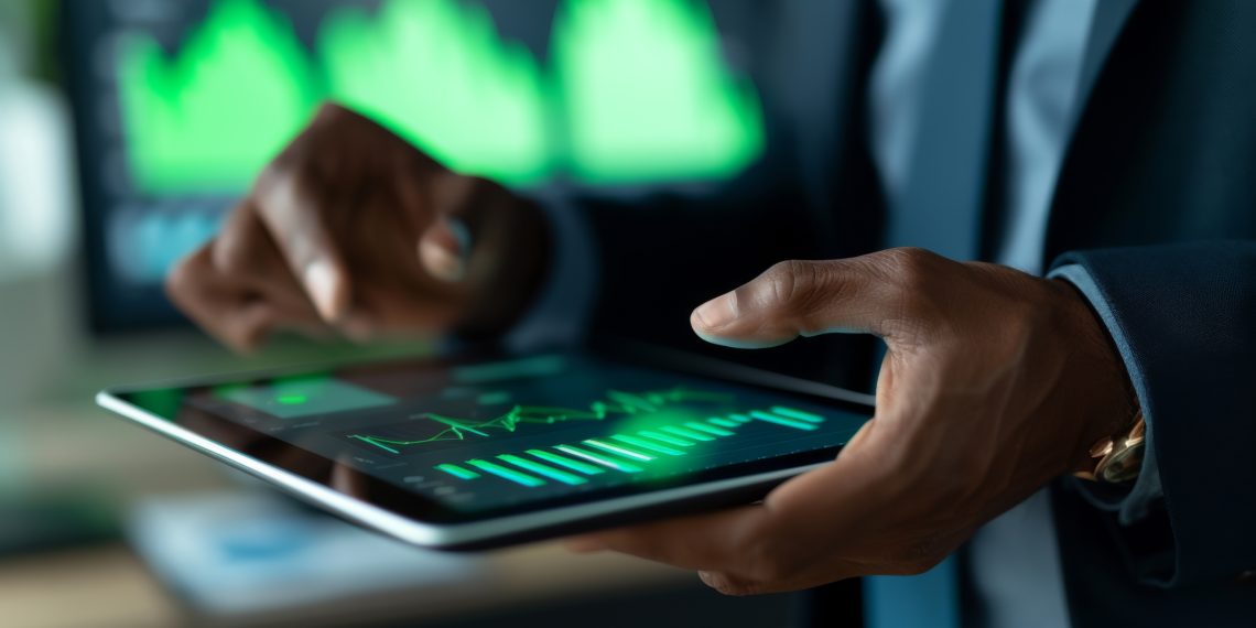 A professional is analyzing financial data on a tablet, interacting with charts and graphs displayed on the screen in a corporate setting.